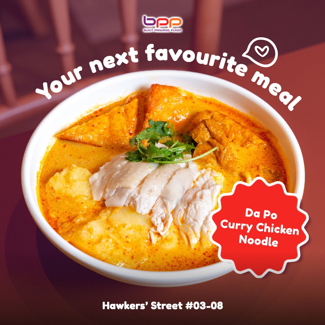 A close-up of a vibrant bowl of curry chicken noodles, rich with broth and tender chicken pieces.