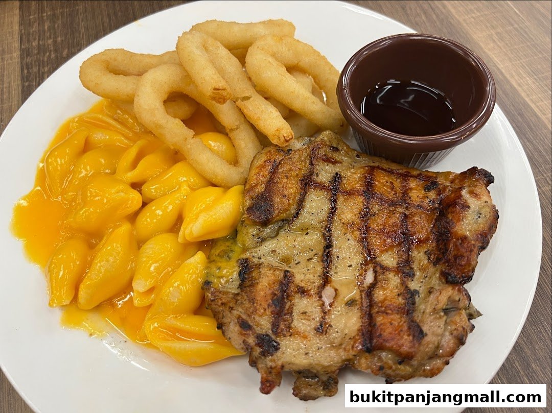 A grilled chicken chop served with macaroni and cheese and onion rings.