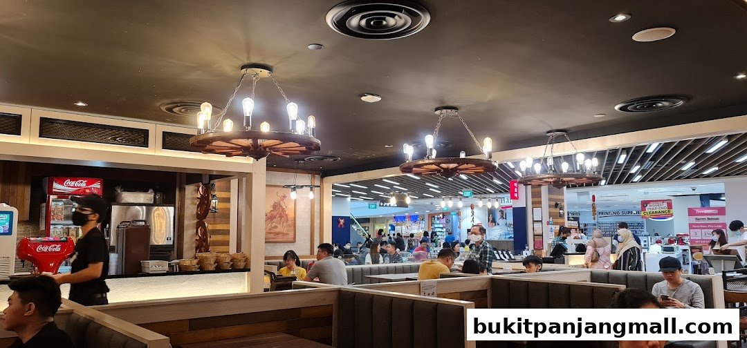 Interior of a restaurant with patrons seated at booths and a staff member at the counter.