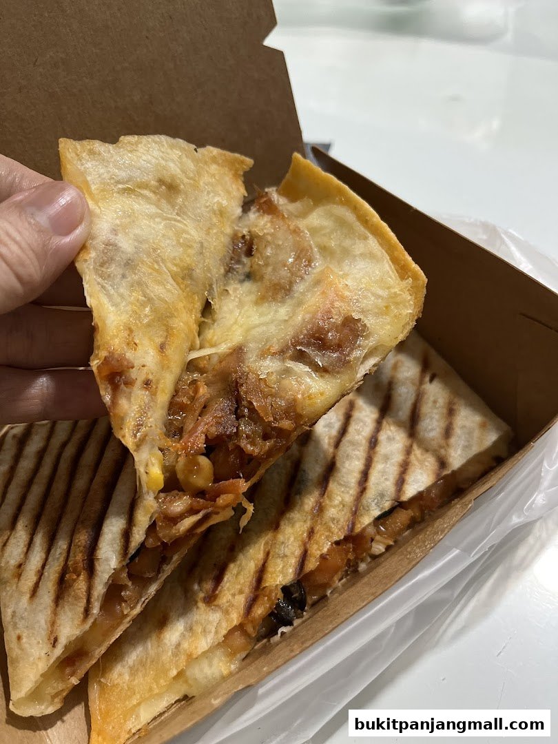 A hand holds a delicious-looking quesadilla filled with savory ingredients.