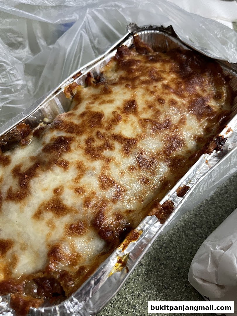 A close-up shot of a delicious-looking lasagna in a foil container, ready to be enjoyed.