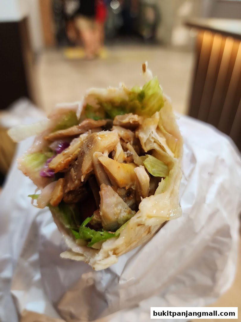 A close-up shot of a delicious shawarma wrap filled with meat, lettuce, and sauce.