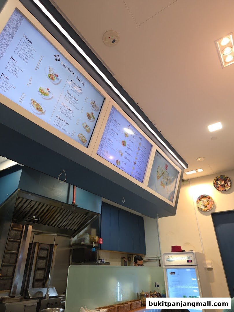A digital menu board displaying various wraps, pitas, kebabs, and rice dishes at ArabiskSG.