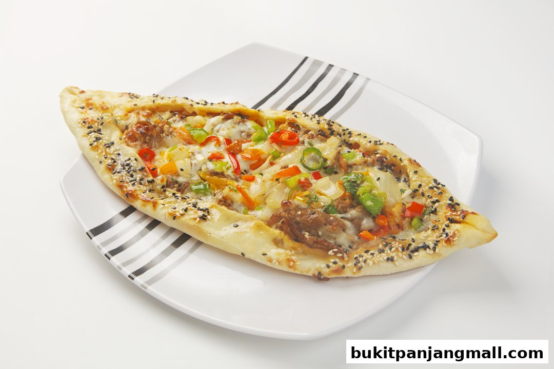 A delicious-looking Turkish pide with meat and vegetables on a white plate.