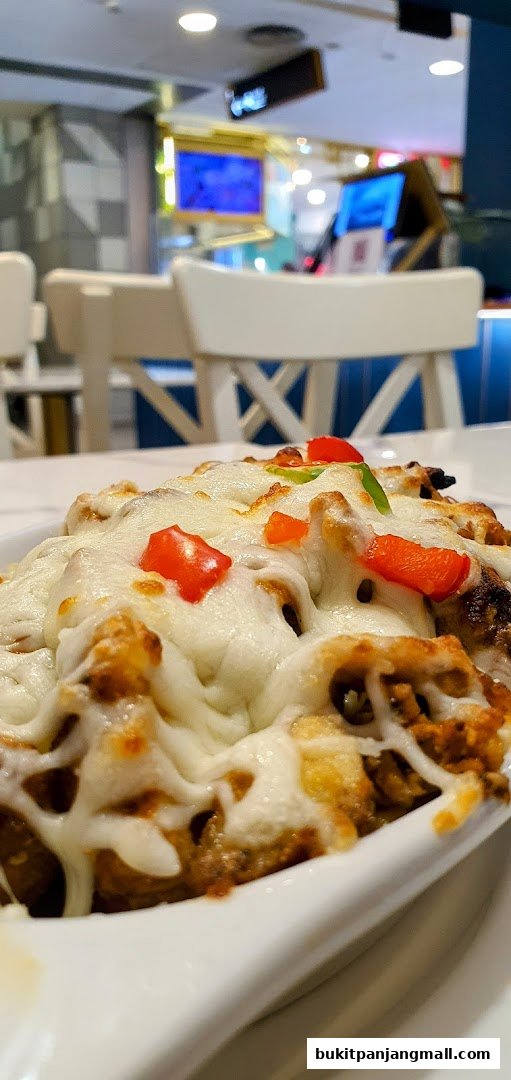 A close-up of a delicious dish topped with melted cheese and diced tomatoes.