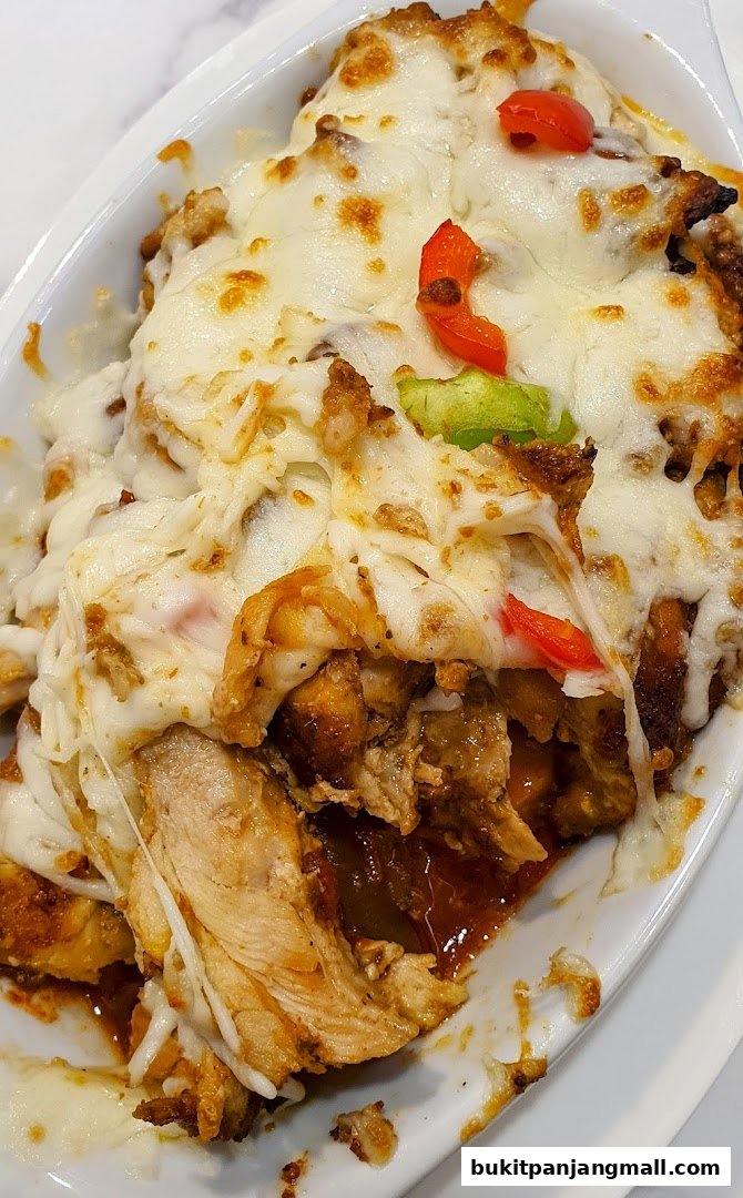 A close-up of a delicious dish with shredded chicken, melted cheese, and peppers.