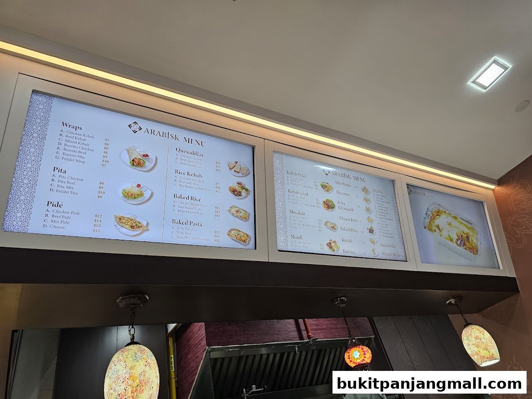 A digital menu board displaying various Arabic food items and prices.