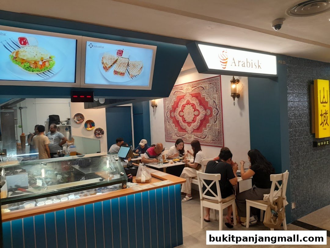 Interior view of ArabiskSG restaurant with customers dining and food displays.