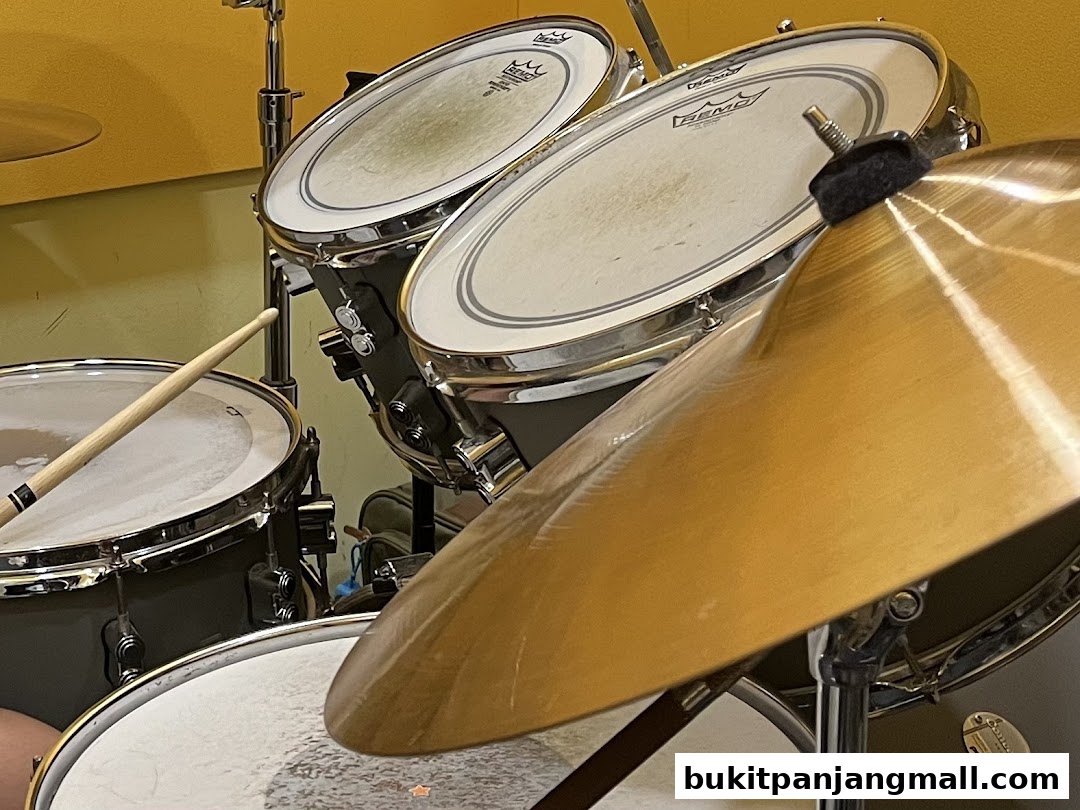 Close-up of a drum kit with a drumstick poised to strike a cymbal.