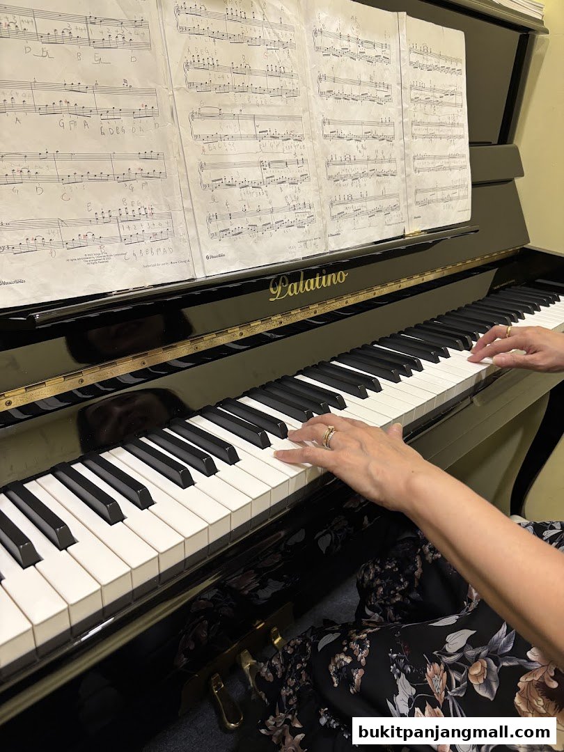 Hands playing a piano with sheet music displayed on the stand.