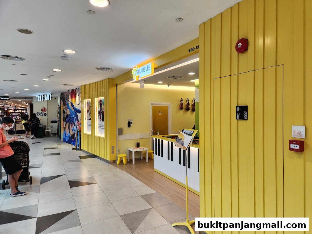 The bright yellow entrance of Aureus Academy with a piano-themed counter and musical instruments displayed.
