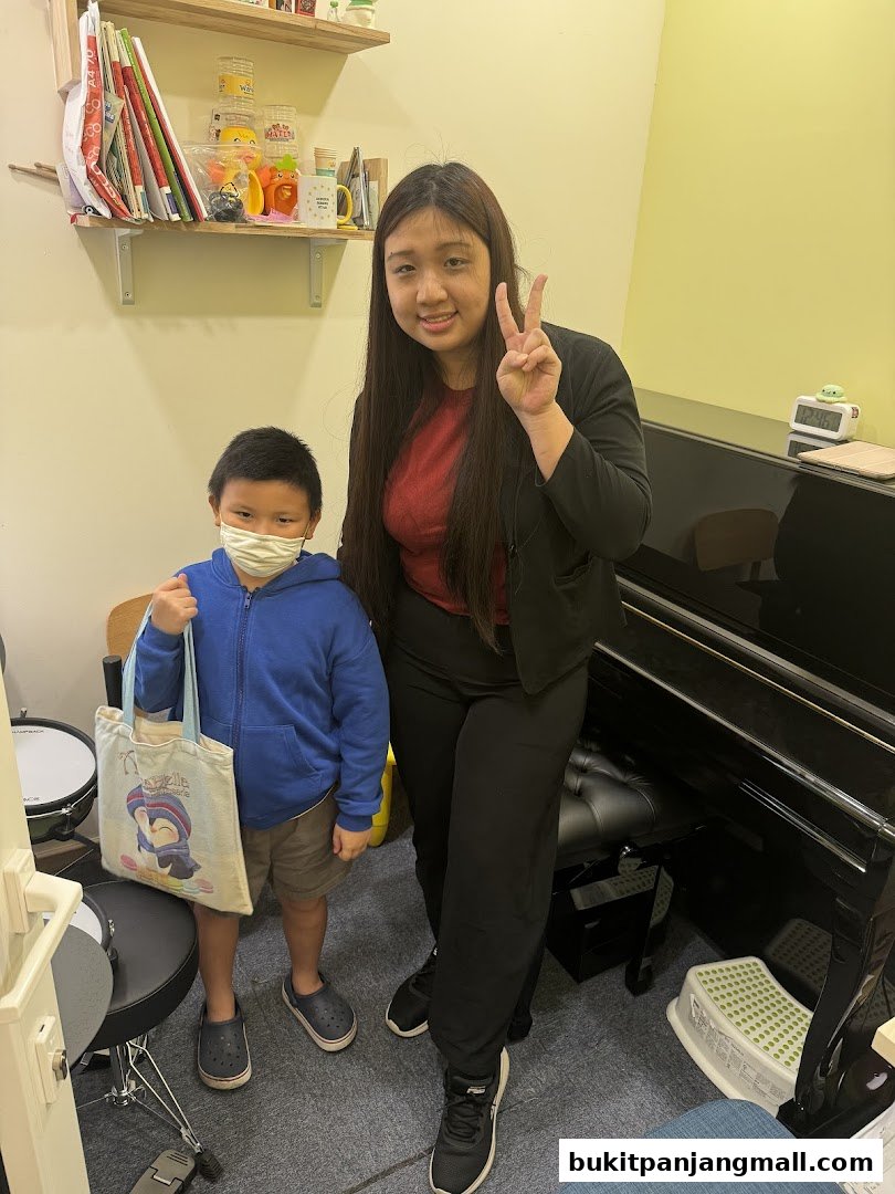 A young boy and a woman pose in front of a piano at Aureus Academy.