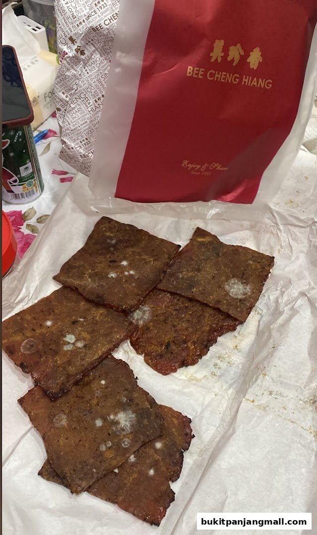 Several pieces of bak kwa with visible mold growth, next to a Bee Cheng Hiang bag.