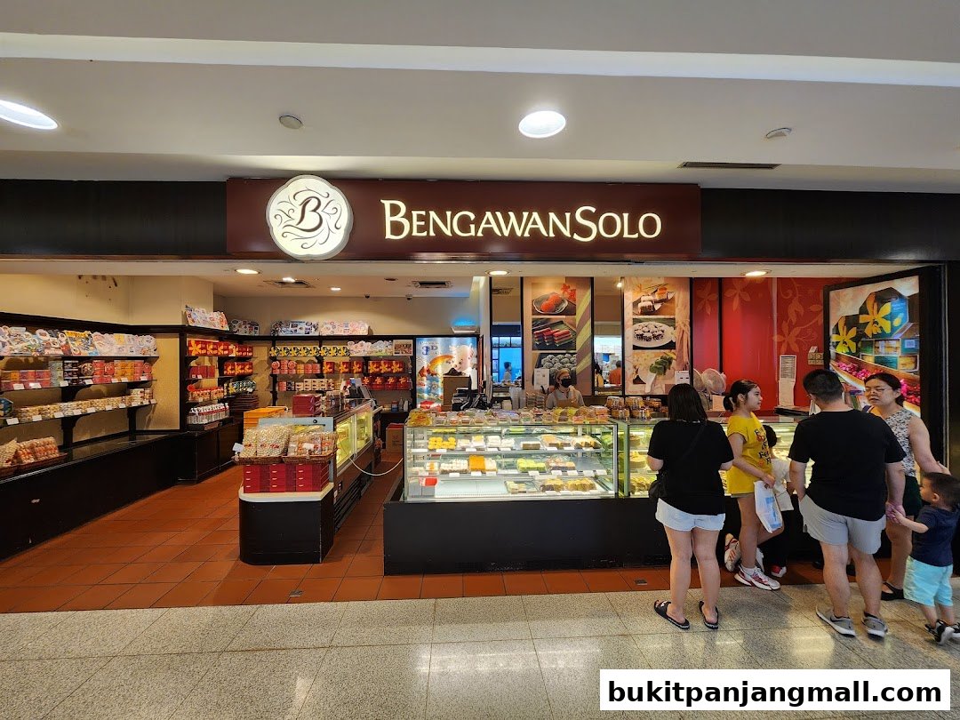A group of people are standing outside a Bengawan Solo shop, which displays cakes and pastries.