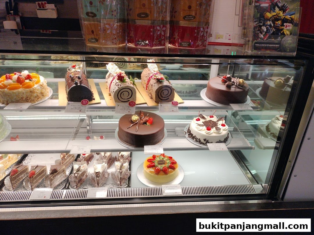 A display case filled with various cakes and pastries, including whole cakes and sliced desserts.