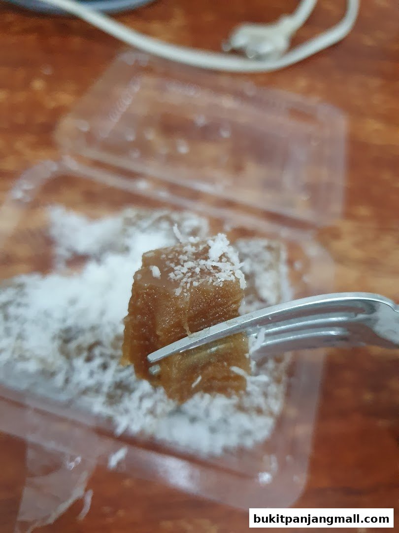 A fork picks up a piece of sweet treat covered in shredded coconut.