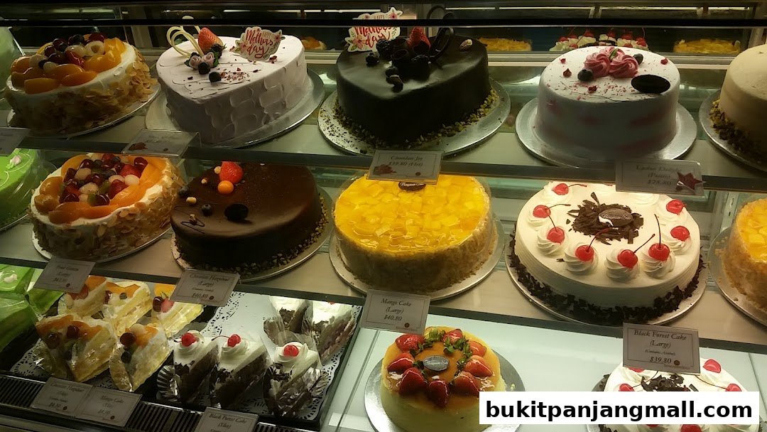 A display case filled with various cakes, including fruit-topped, chocolate, and cream cakes.