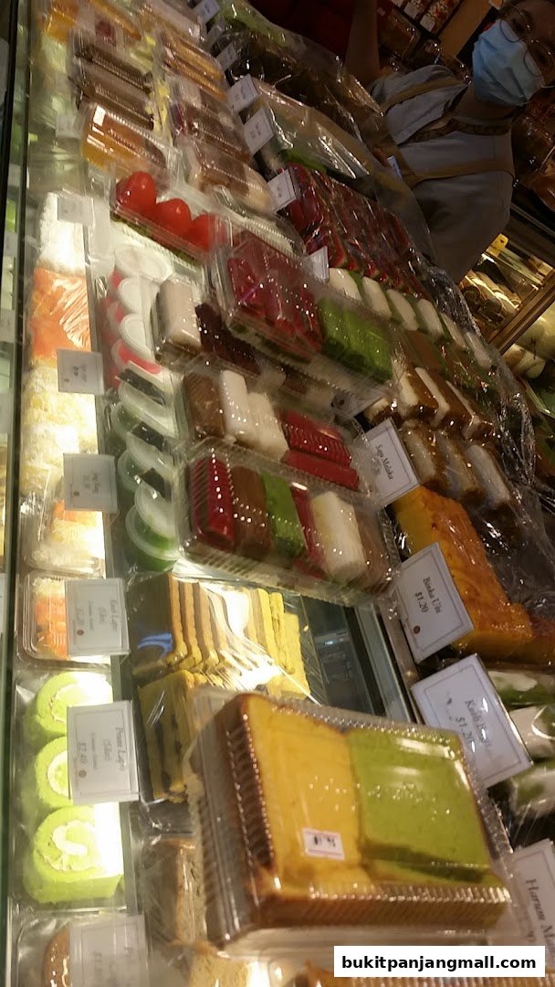 A display case filled with various colorful cakes and pastries, neatly packaged.