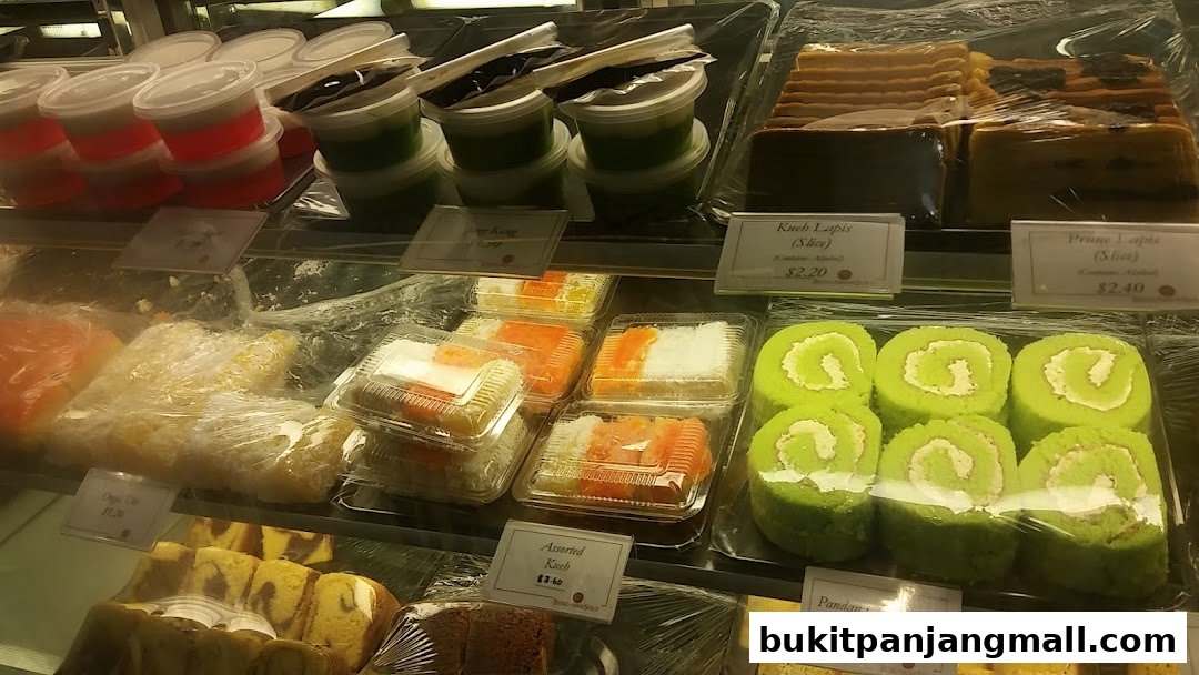 A display case filled with various colorful cakes and desserts, neatly packaged.