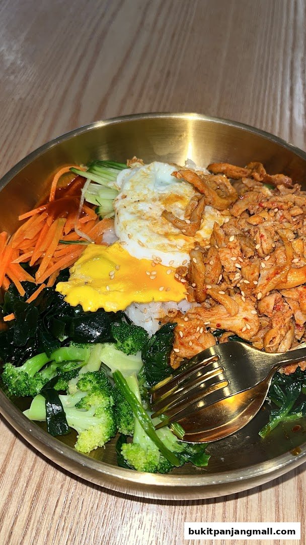 A close-up of a delicious bibimbap dish with chicken, egg, and fresh vegetables.