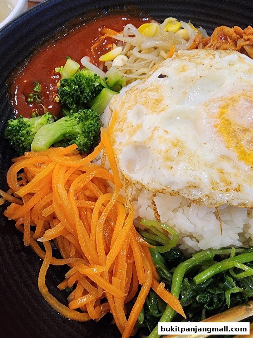 A close-up of a delicious bibimbap dish with rice, vegetables, and a fried egg.