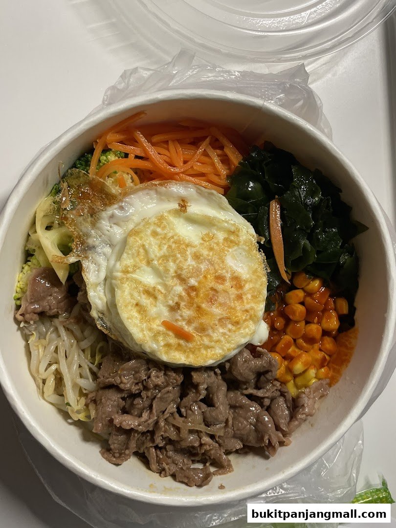 A delicious bowl of bibimbap with beef, vegetables, and a fried egg.