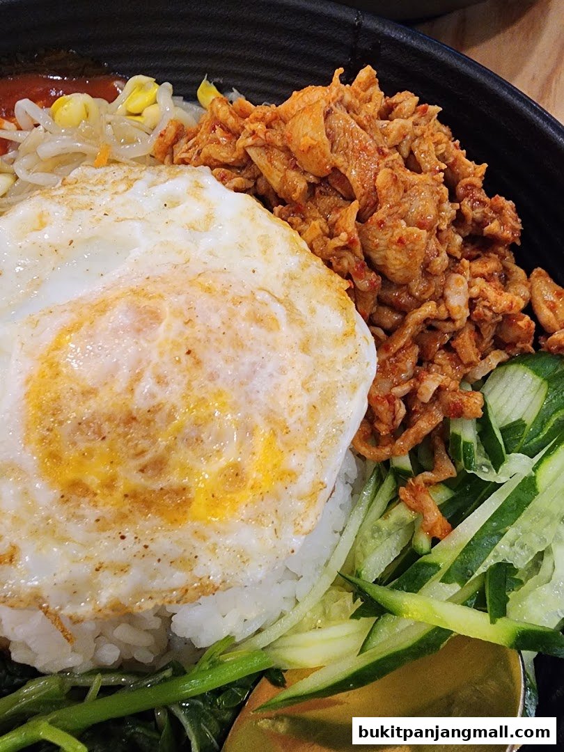 A close-up of a delicious bibimbap with a fried egg, seasoned meat, and fresh vegetables.