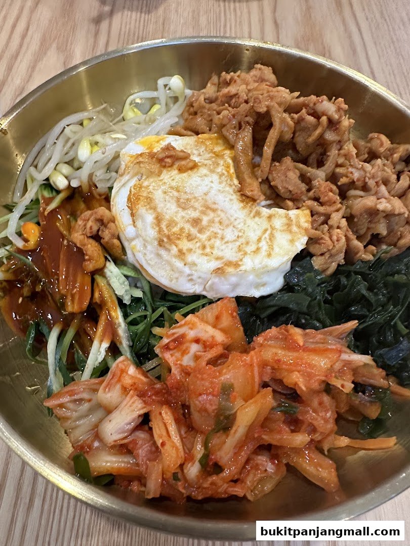 A close-up of a delicious bibimbap dish with a fried egg, meat, vegetables, and kimchi.