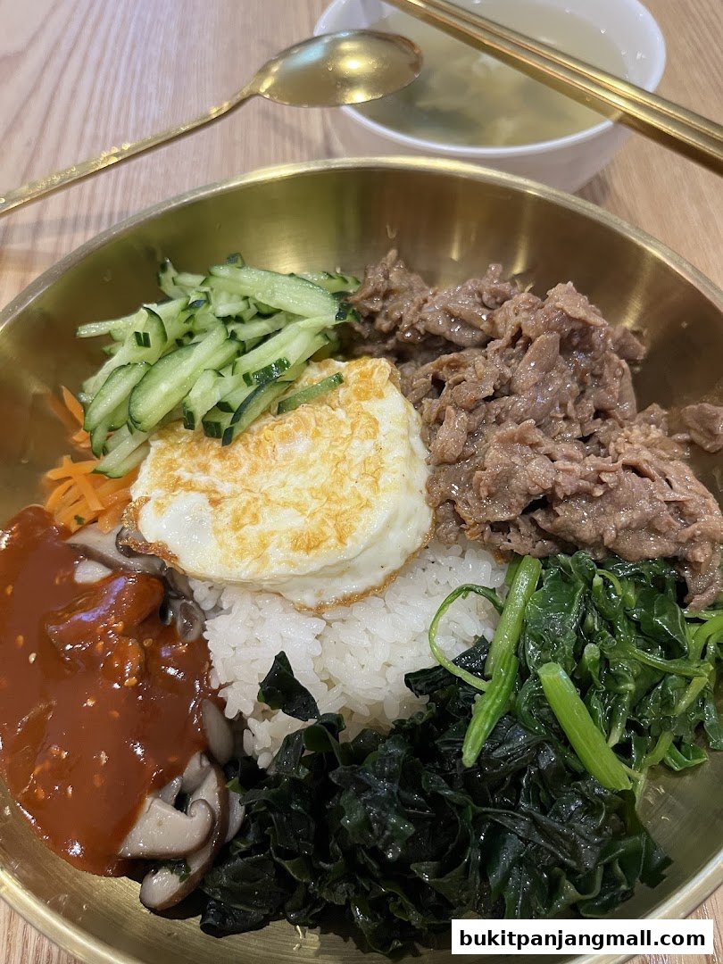 A delicious bowl of bibimbap with rice, beef, egg, vegetables, and sauce.