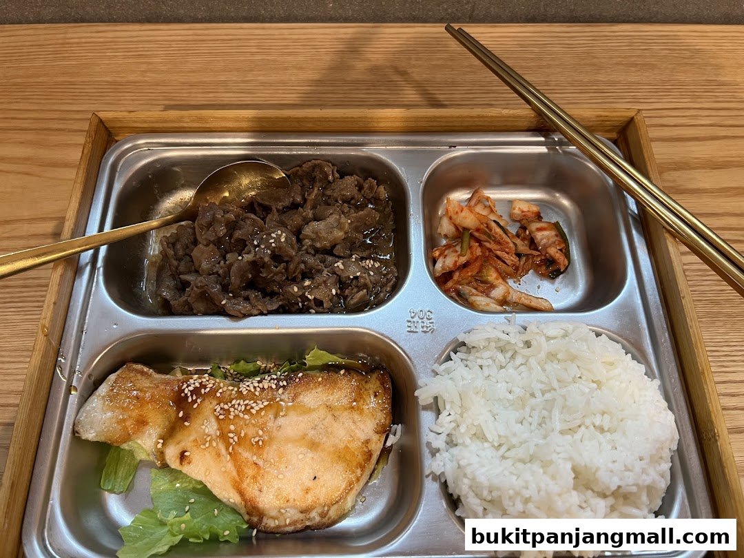 A bento box with grilled fish, bulgogi beef, kimchi, and rice.