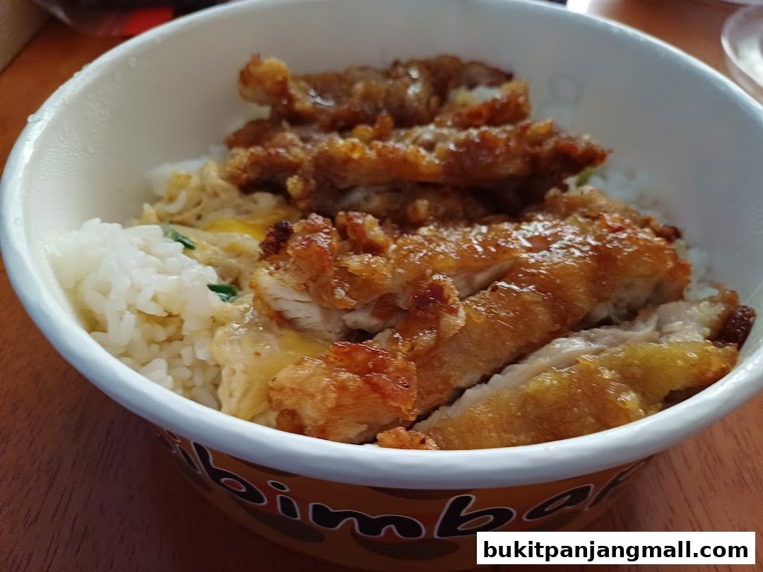 A close-up of a delicious bibimbap dosirak with crispy fried chicken and rice.