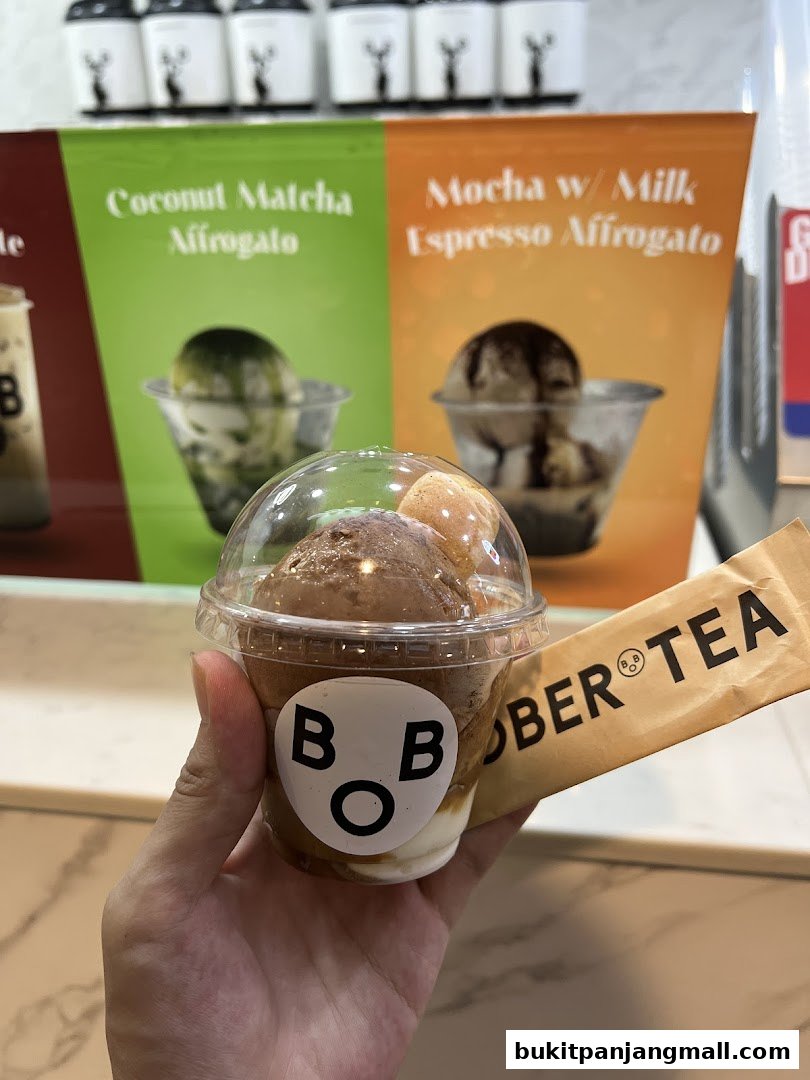 A hand holds a Bober Tea affogato with a menu board in the background.