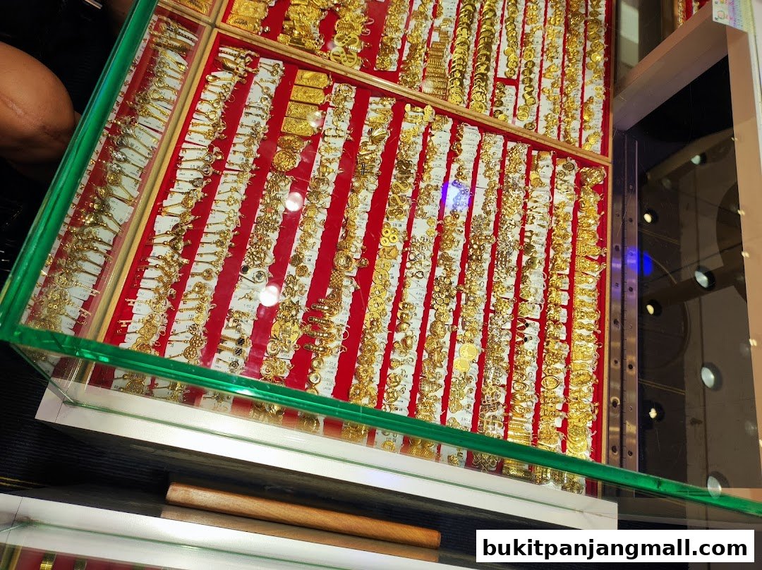 A display case filled with numerous gold pendants and charms, arranged on a red background.