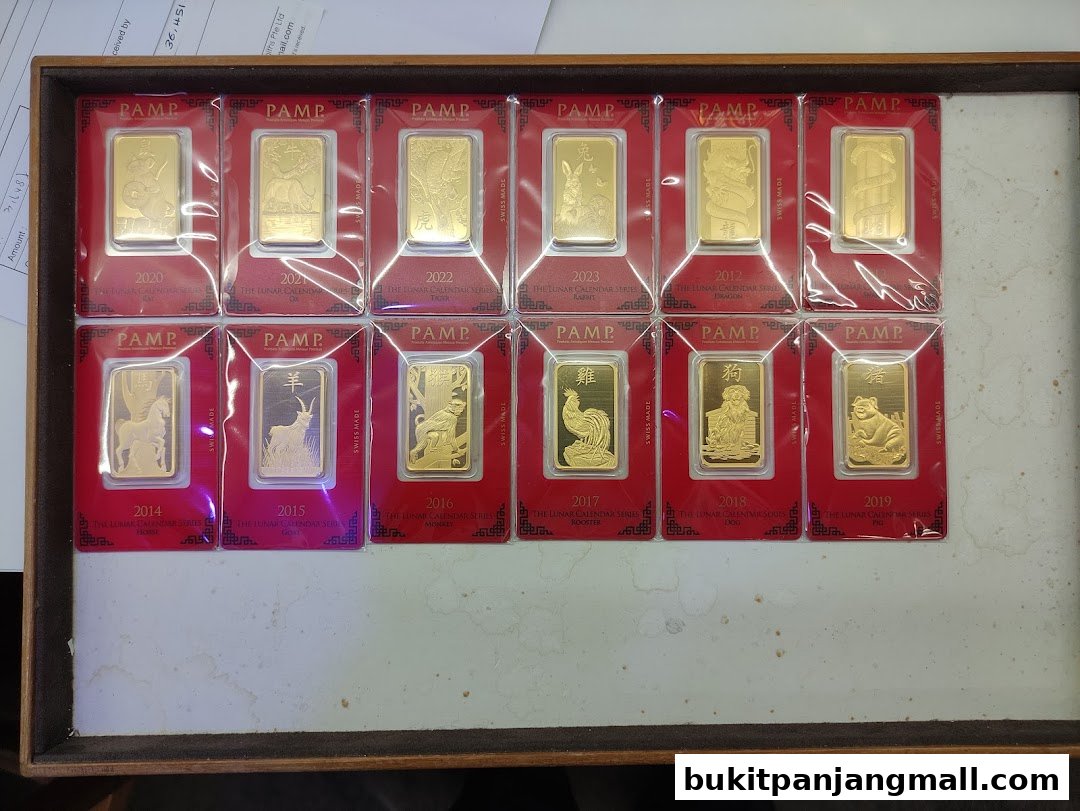 A collection of PAMP gold bars featuring lunar calendar animals, displayed in a wooden tray.