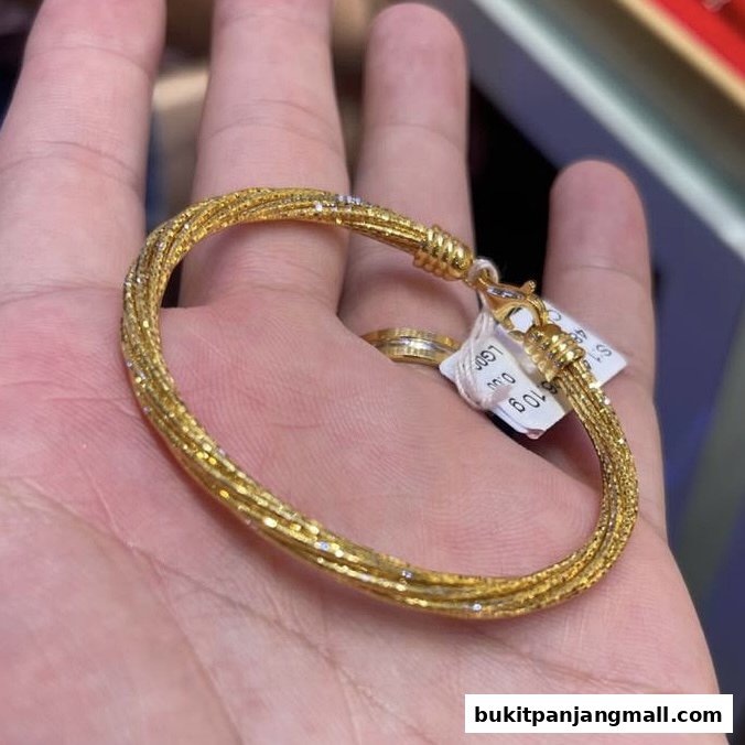 A hand holds a sparkling gold bracelet with a price tag attached.