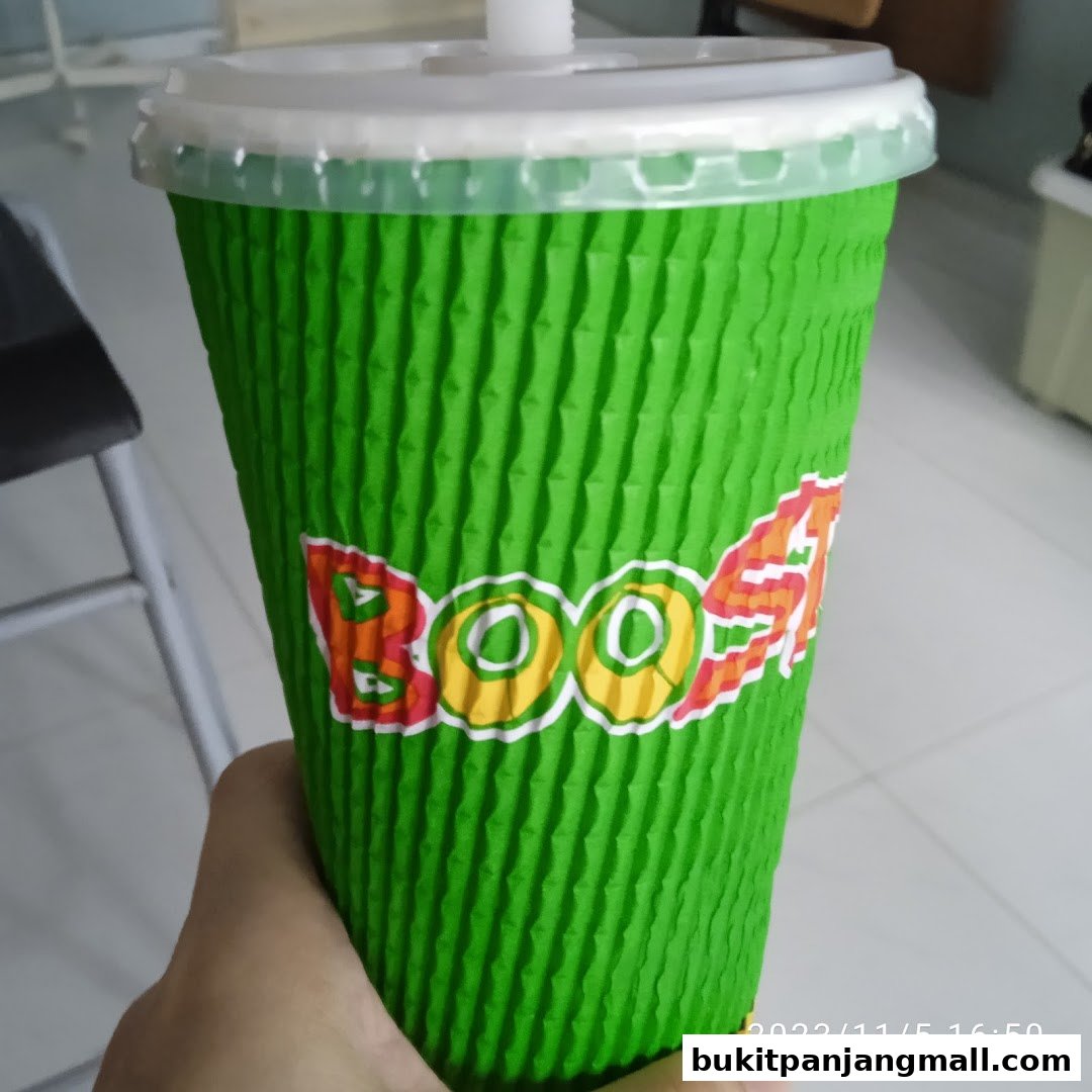 A hand holds a green textured cup with the Boost Juice logo.