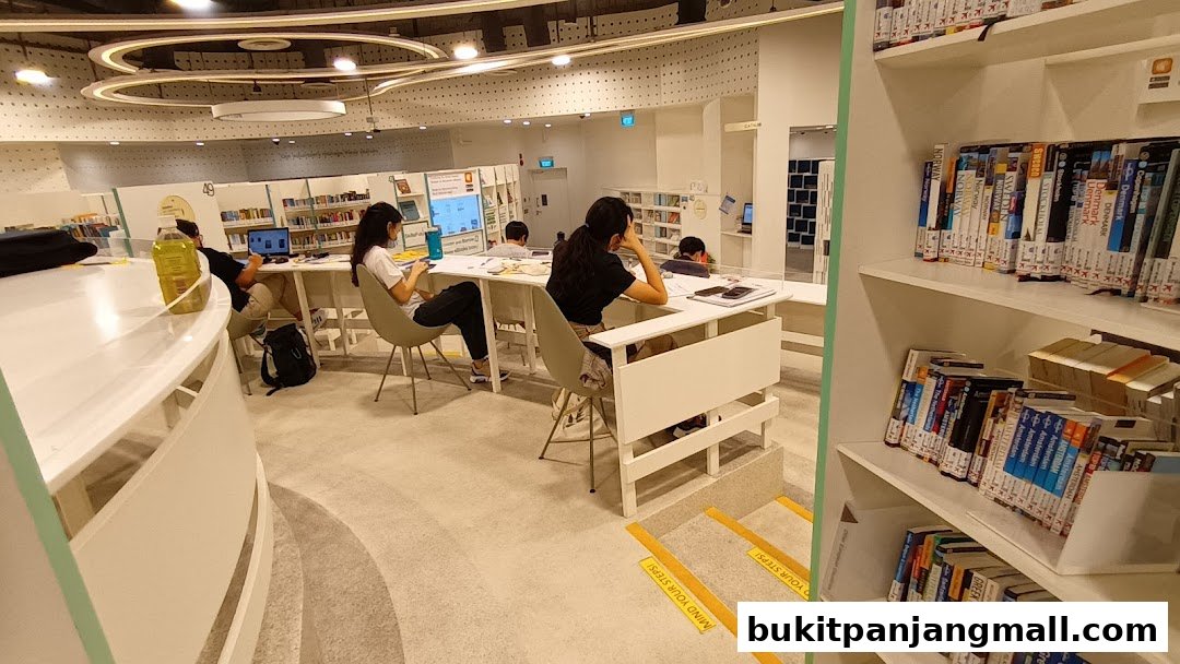 People studying at tables in a modern library with bookshelves visible.