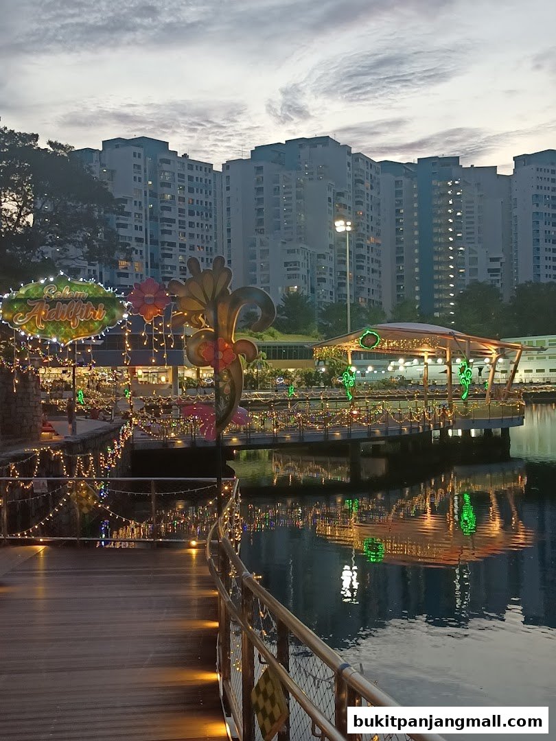 A waterfront walkway decorated with festive lights and a 'Selamat Aidilfitri' sign.