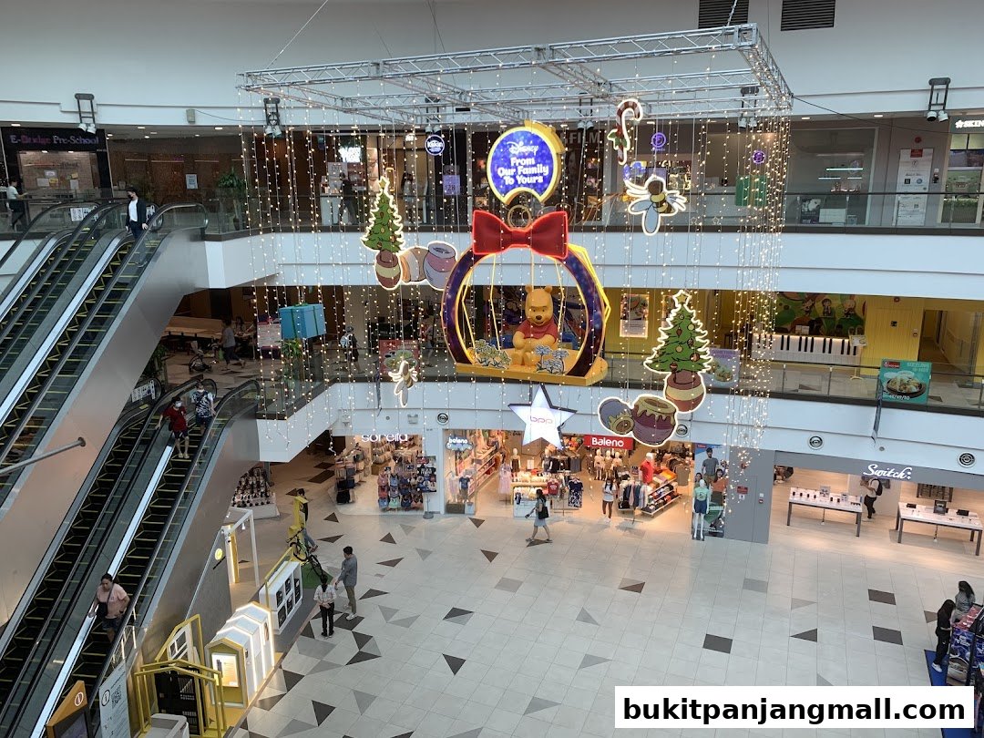 A mall interior with escalators, shops, and festive Winnie the Pooh decorations.