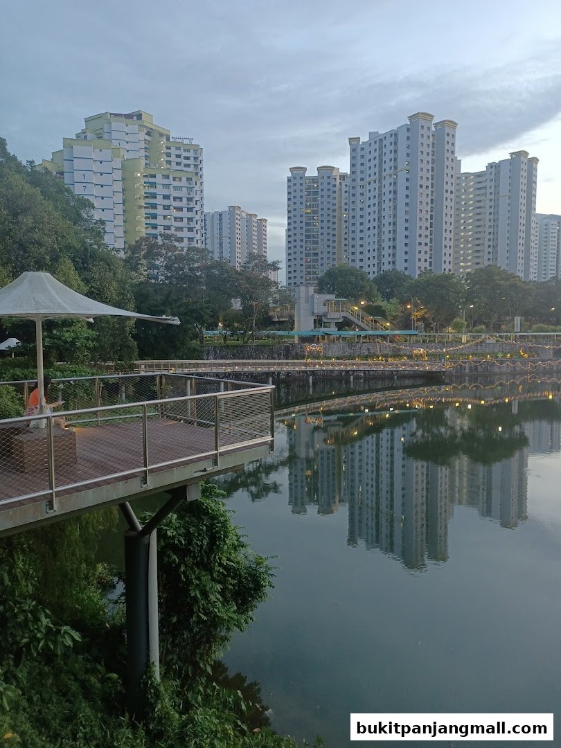 A scenic view of a waterfront promenade with apartment buildings reflected in the water.
