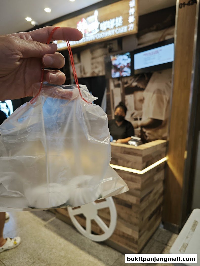 A hand holds a plastic bag with Tutu Kueh from Chinatown Tans.
