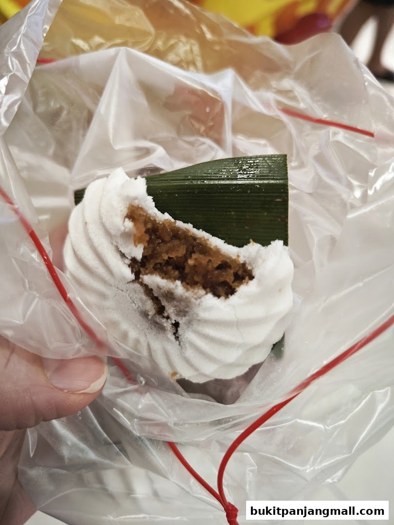 A close-up of a Tutu Kueh dessert, partially eaten, wrapped in plastic.