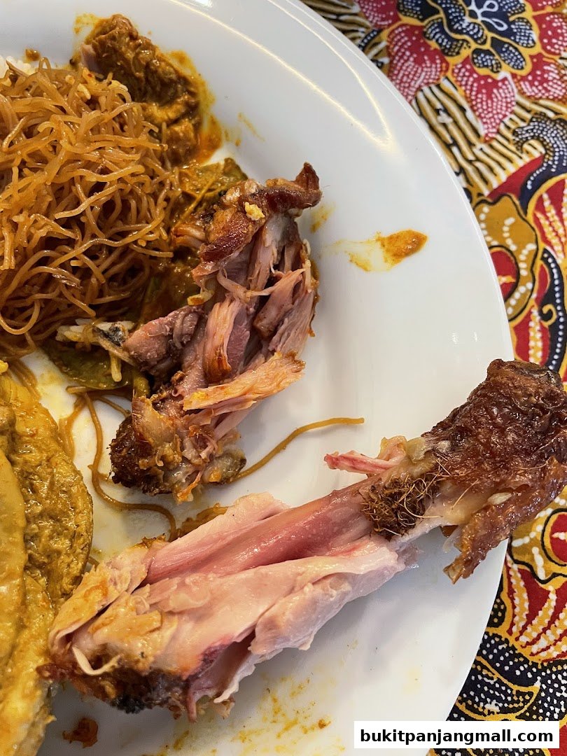 A close-up of a plate of nasi lemak with tender, shredded chicken and noodles.