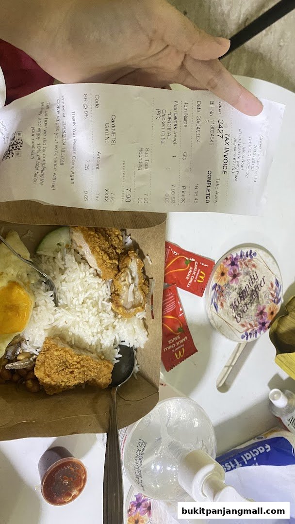 A close-up of a Nasi Lemak meal with a receipt and hand sanitizer.