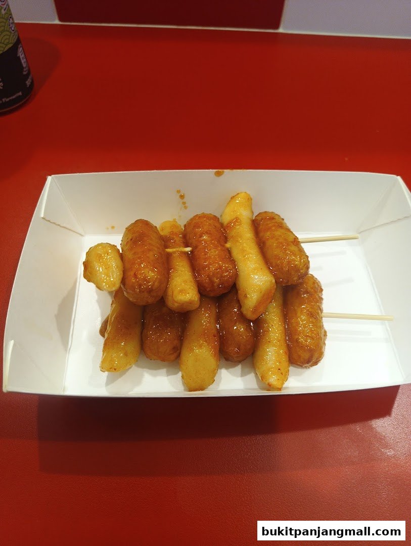 A white tray filled with Korean fried chicken skewers on a red surface.
