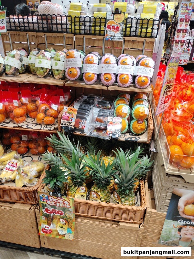A display of fresh fruits including pineapples, persimmons, and oranges, neatly arranged in baskets and packaging.