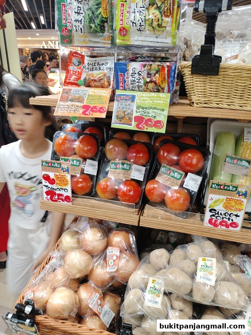 A variety of fresh produce and ready-to-cook meals are displayed on shelves in a brightly lit store.