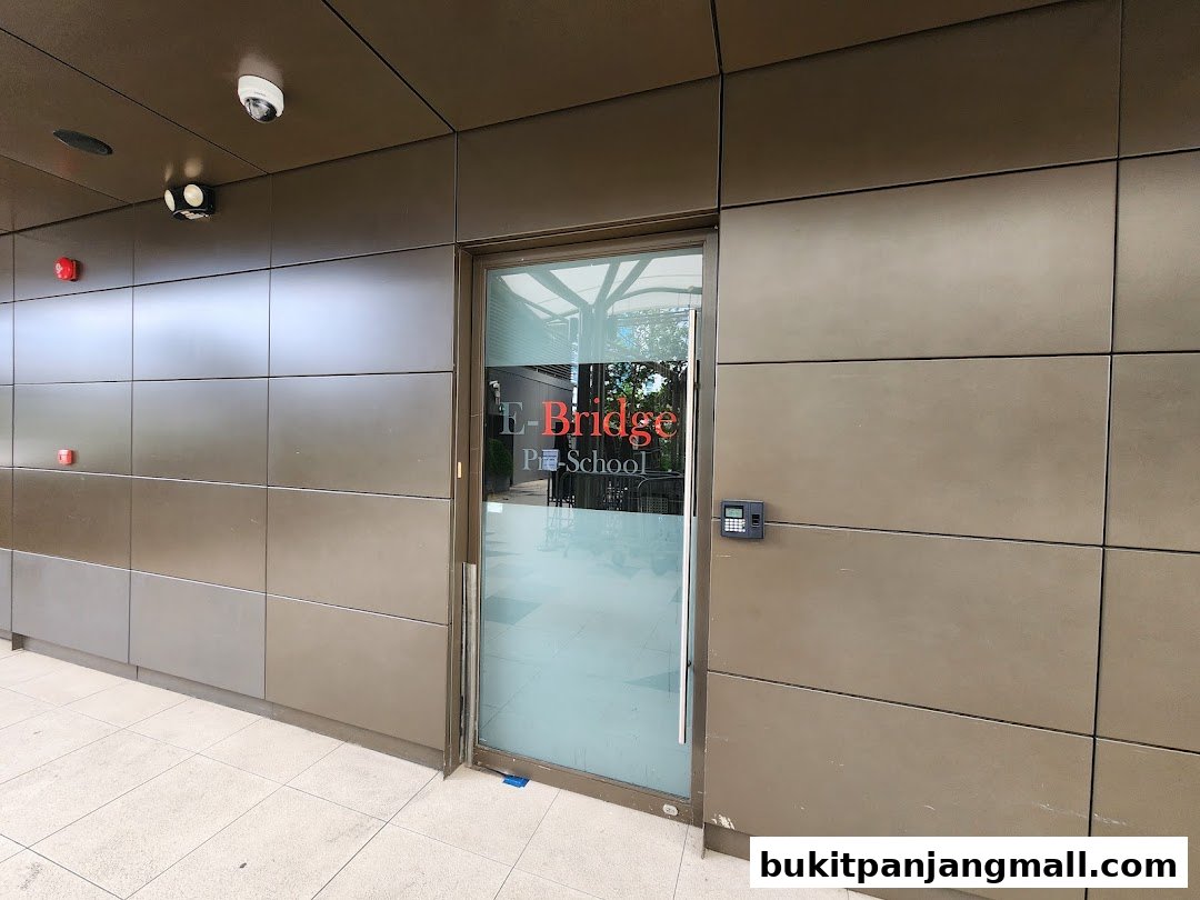 The entrance to E-Bridge Pre-School Bukit Panjang, featuring a glass door and modern facade.