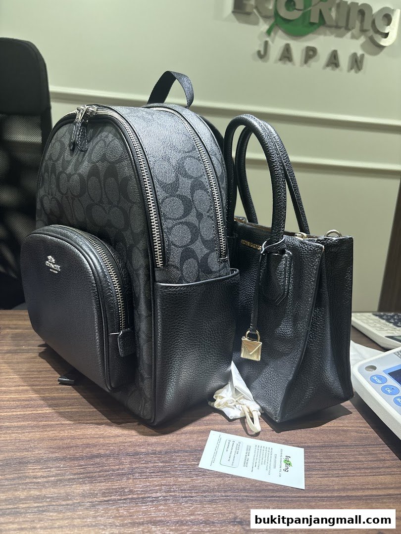 A black Coach backpack and a black Michael Kors handbag displayed on a wooden surface.