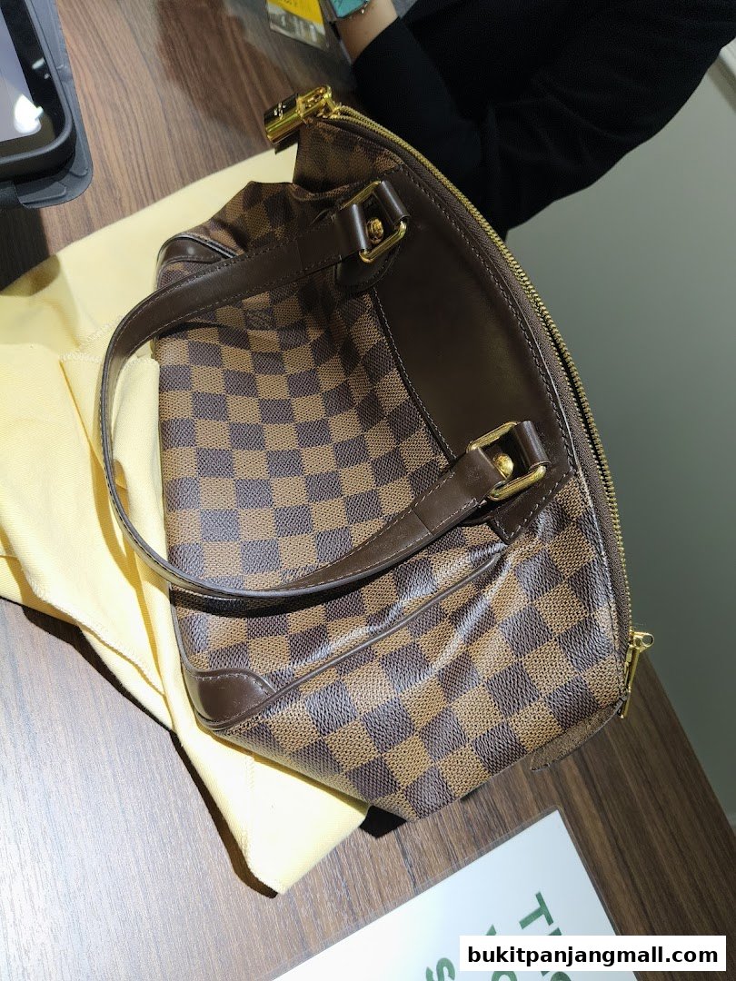 A close-up shot of a brown checkered designer handbag on a wooden surface.